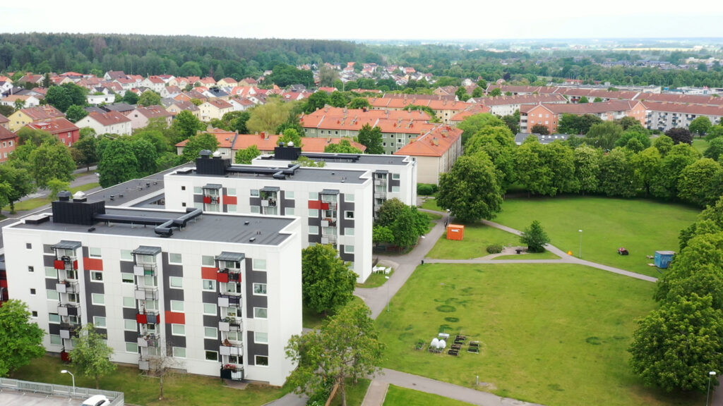 Tre vita byggnader med grönska runtom