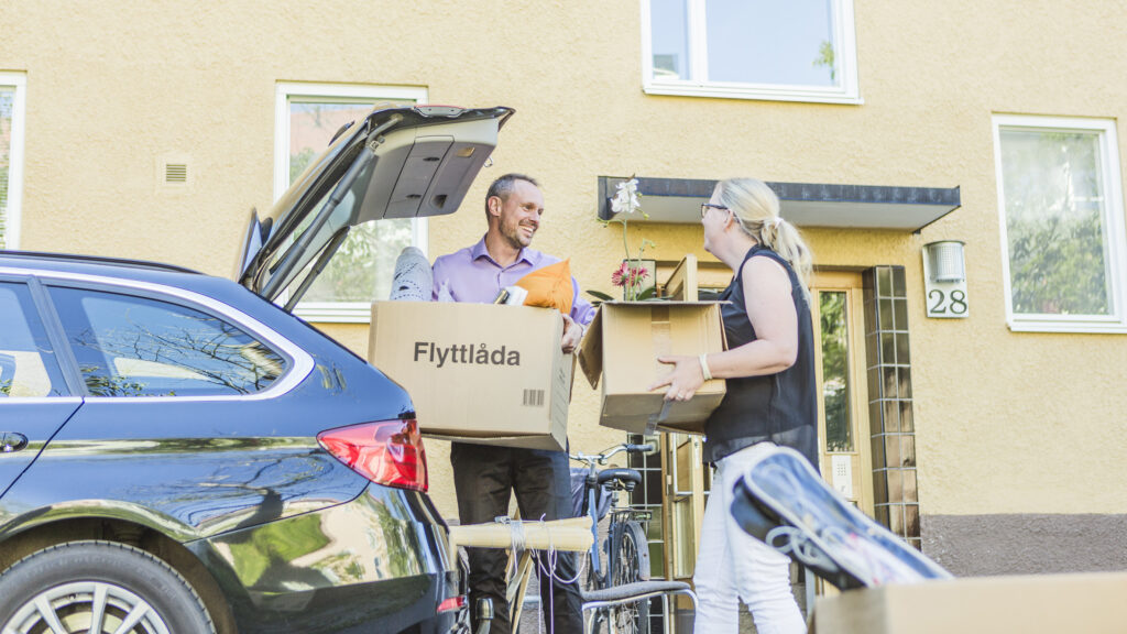 En man och en kvinna håller varsin flyttlåda och skrattar