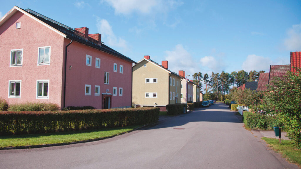 Gata, buskar och två bostadshus
