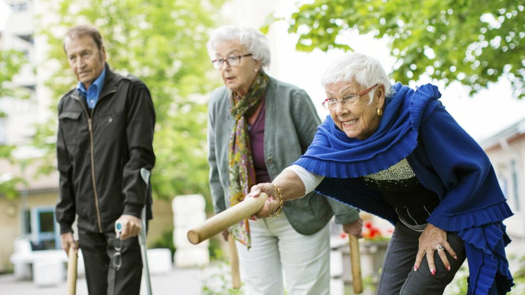 äldre kvinnor och man spelar kubb