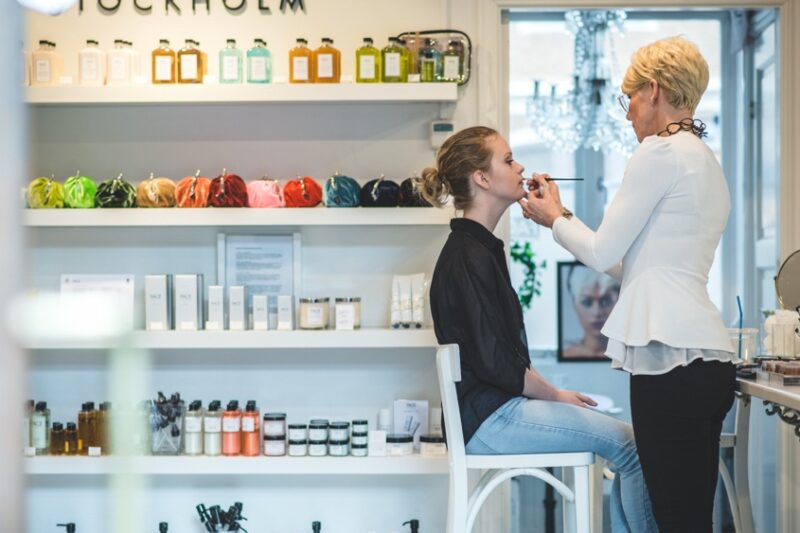 tjej sitter i en affärs och blir sminkad av en makeupartist