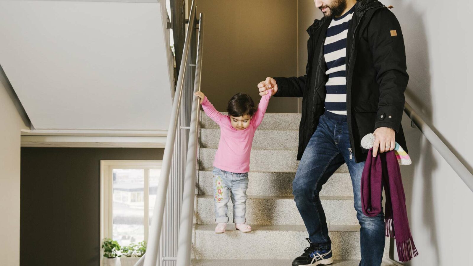 pappa håller litet barn i handen när de går i trappan