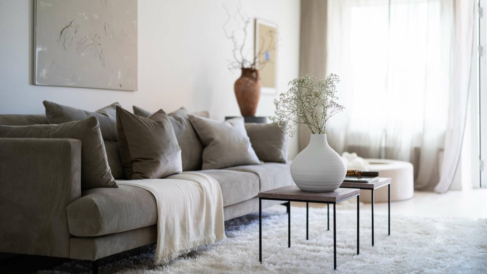 vardagsrum med grå soffa och soffbord med blommor