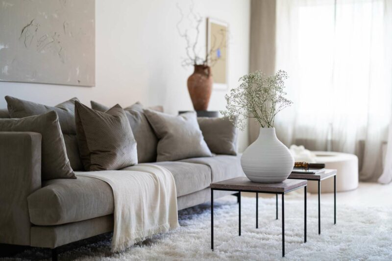 vardagsrum med grå soffa och soffbord med blommor