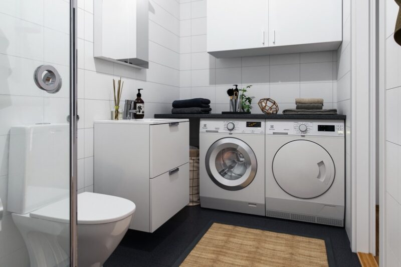 helkaklat vitt badrum med tvättmaskin och torktumlare